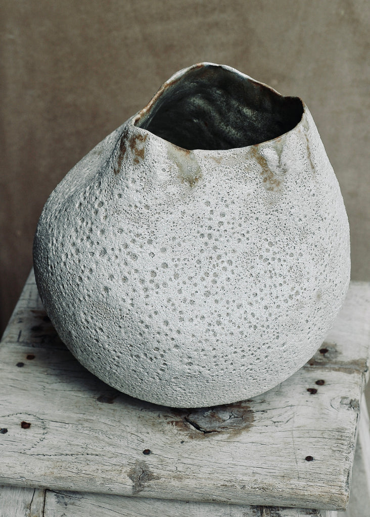This piece is hand-built, coiled. The interior is finished in a white glaze. The exterior is finished in a volcanic glaze. Where the two glazes meet resulted in warm tones. The piece measures 9 inches in diameter and 9.5 inches tall.  Edit alt text