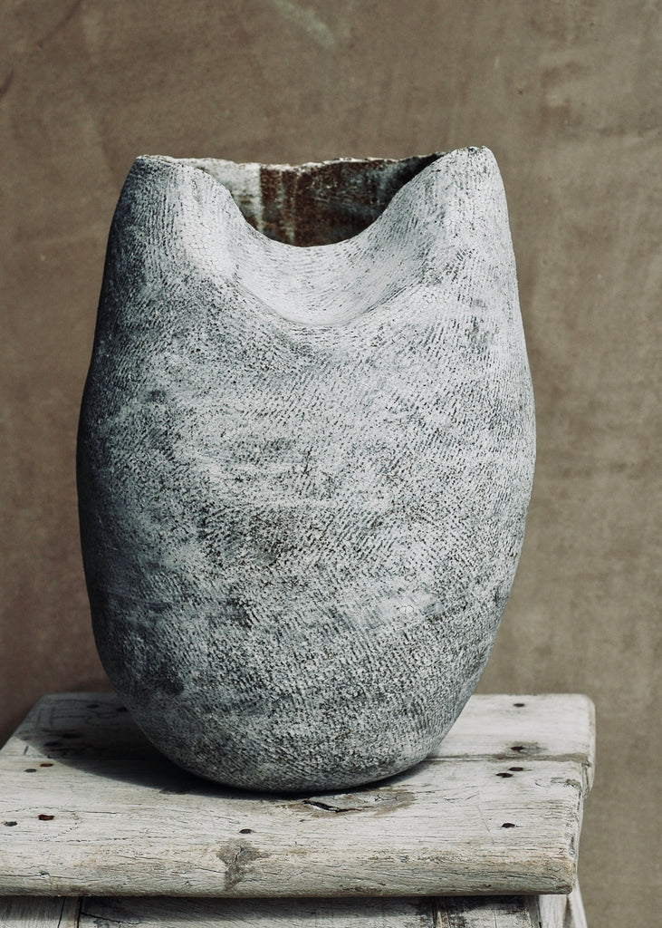 Hand-built, coiled vessel. Exterior is scored for texture and finished in white slip. Dimensions are 8 inches in diameter and 11 inches tall.