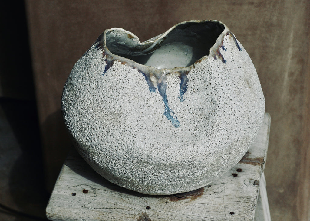 This piece is hand-built, coiled and mid-fired.  It is finished in white glaze on the interior and a volcanic glaze on the exterior.  Where the two glazes interact, magic happens.  In this case, the mix of glazes during the firing resulted in beautiful blue tones.  11.5 inches in diameter and 9 inches tall.